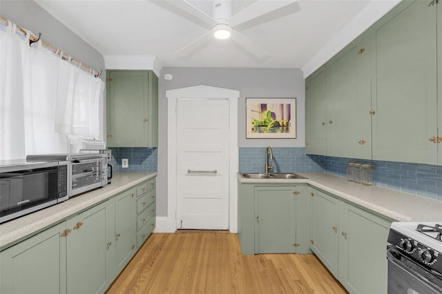 kitchen featuring backsplash, green cabinets, sink, light hardwood / wood-style flooring, and white range oven