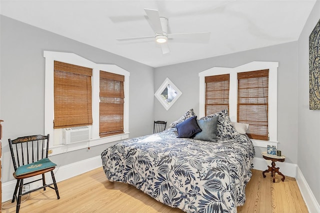 bedroom with ceiling fan, cooling unit, and wood-type flooring