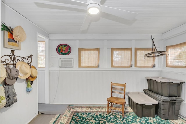 sitting room with a wall mounted AC and ceiling fan