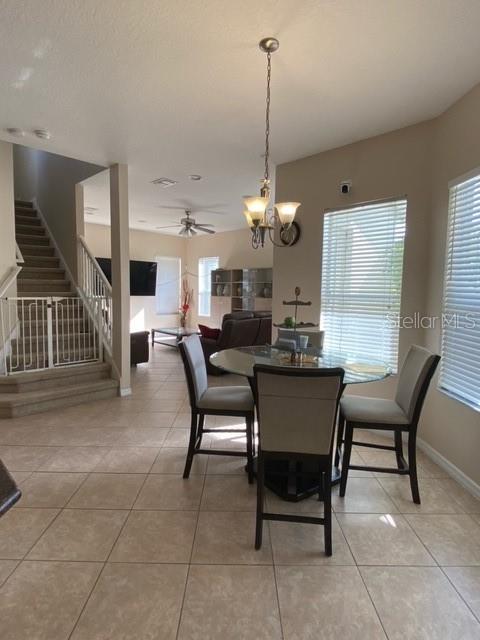 dining area with plenty of natural light, light tile patterned floors, and ceiling fan with notable chandelier