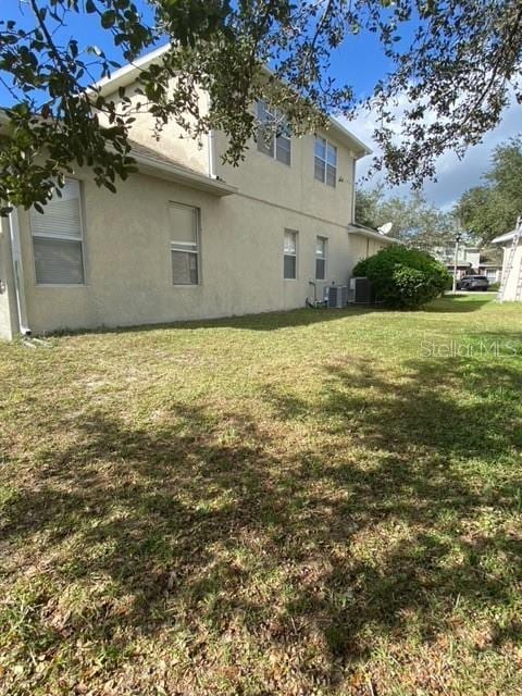 view of side of home with cooling unit and a lawn