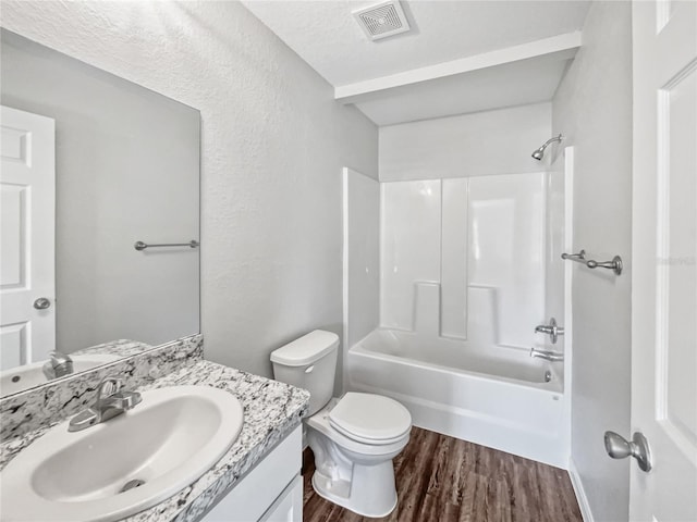 full bathroom with vanity, shower / tub combination, hardwood / wood-style flooring, toilet, and a textured ceiling