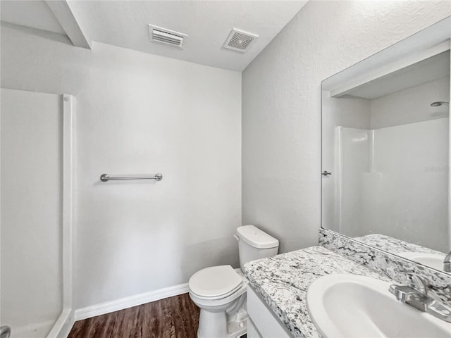 bathroom featuring hardwood / wood-style floors, vanity, toilet, and a shower