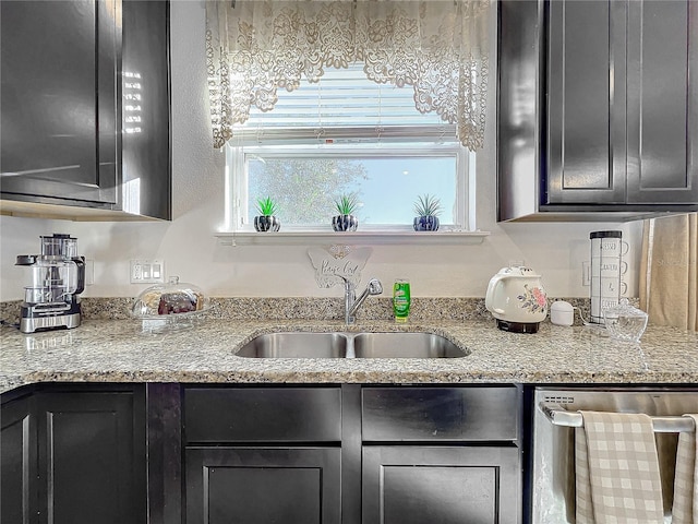 kitchen with stainless steel dishwasher, light stone counters, and sink