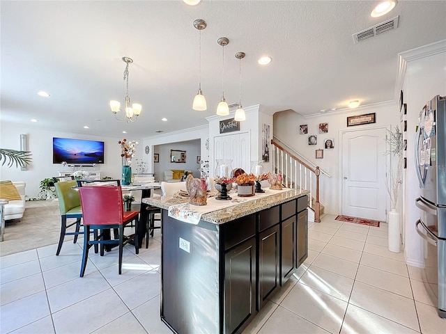 kitchen with ornamental molding, dark brown cabinetry, decorative light fixtures, a notable chandelier, and a center island