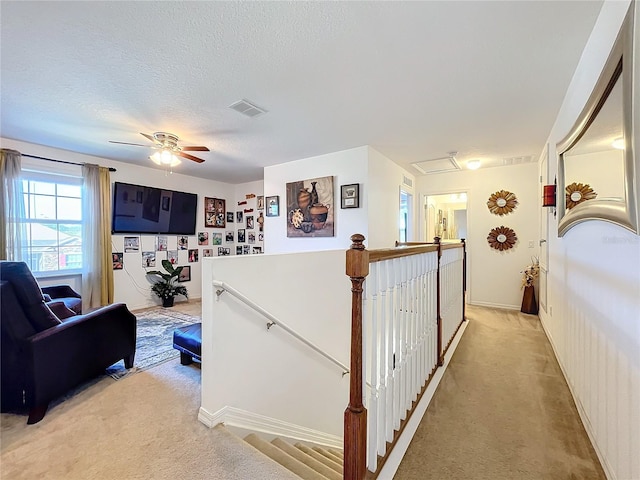 corridor featuring light carpet and a textured ceiling