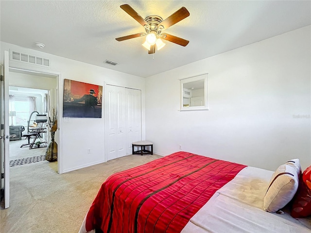 carpeted bedroom featuring ceiling fan, a closet, and a textured ceiling