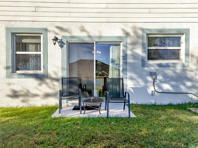 view of exterior entry featuring a patio and a lawn