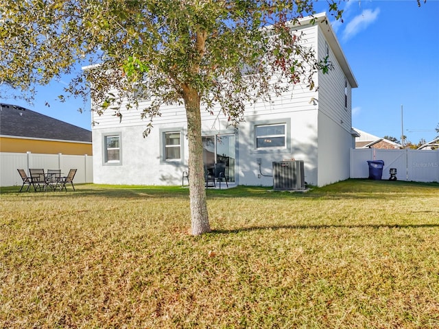 rear view of property featuring a lawn and central AC