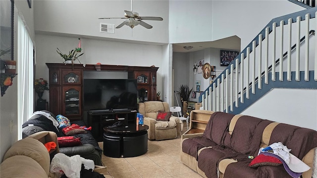 living room with ceiling fan, a towering ceiling, and light tile patterned floors