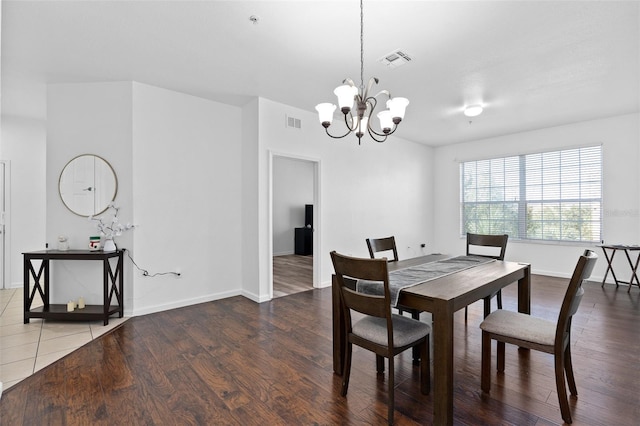 dining space with hardwood / wood-style floors and an inviting chandelier