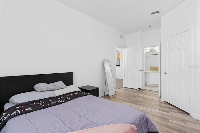 bedroom featuring ensuite bath and light hardwood / wood-style flooring