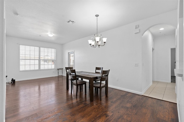 dining space with dark wood-type flooring and a notable chandelier