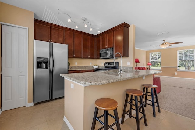 kitchen with light carpet, sink, ceiling fan, appliances with stainless steel finishes, and a breakfast bar area