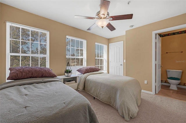 bedroom with ceiling fan, light colored carpet, and connected bathroom