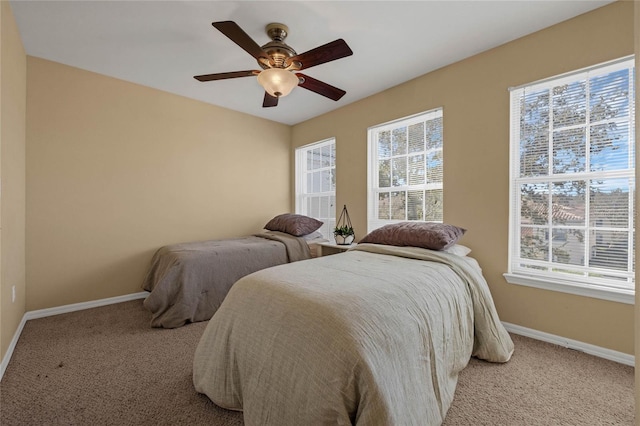 bedroom featuring ceiling fan, light carpet, and multiple windows