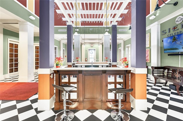 bar with decorative light fixtures, crown molding, and a high ceiling