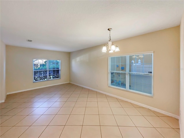 tiled empty room featuring a chandelier