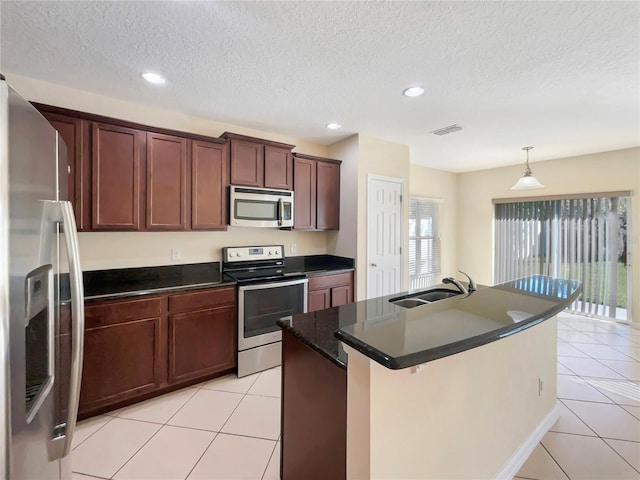 kitchen with appliances with stainless steel finishes, a textured ceiling, a kitchen island with sink, and sink