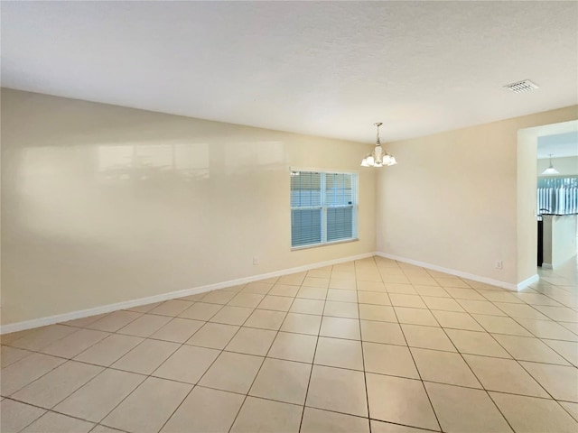 spare room featuring light tile patterned flooring and an inviting chandelier