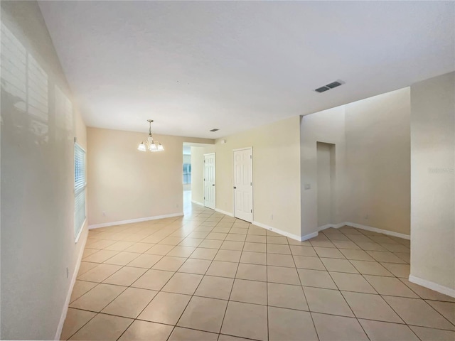 tiled empty room featuring a chandelier