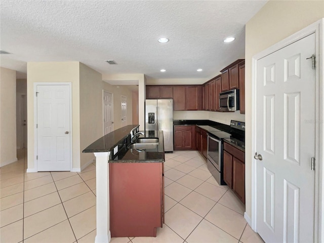 kitchen featuring light tile patterned floors, stainless steel appliances, a kitchen island with sink, and sink