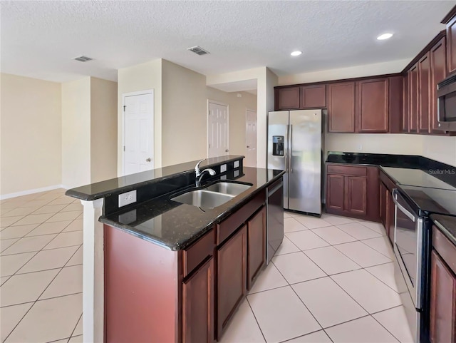 kitchen with sink, stainless steel appliances, a textured ceiling, a center island with sink, and light tile patterned floors