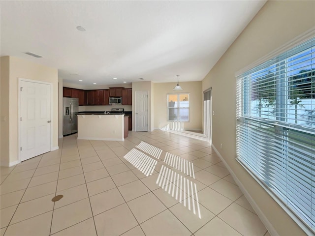 kitchen featuring appliances with stainless steel finishes, dark brown cabinets, light tile patterned floors, pendant lighting, and a center island