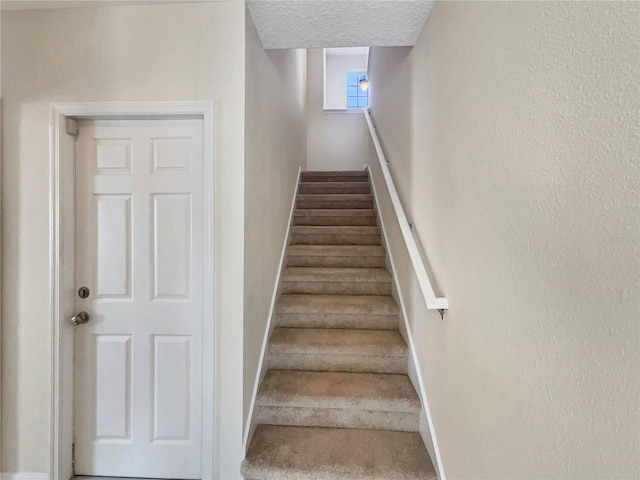 stairway featuring a textured ceiling