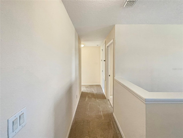 hallway featuring carpet and a textured ceiling