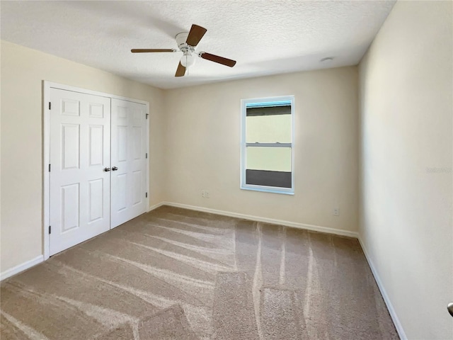 unfurnished bedroom featuring a textured ceiling, a closet, ceiling fan, and light colored carpet