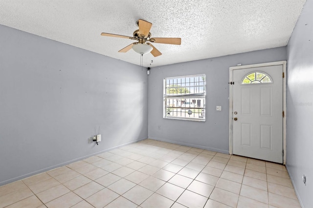 tiled entryway with ceiling fan and a textured ceiling