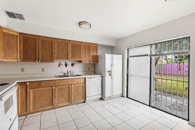 kitchen with sink, light tile patterned floors, and white appliances