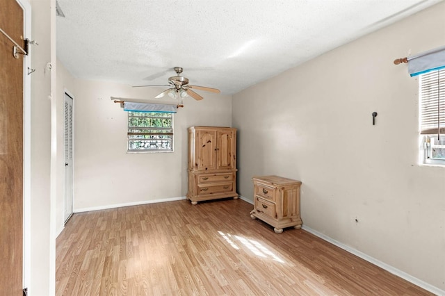 spare room with ceiling fan, light hardwood / wood-style floors, and a textured ceiling