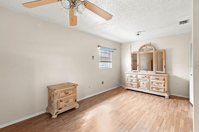 bedroom with a textured ceiling, light hardwood / wood-style flooring, and ceiling fan