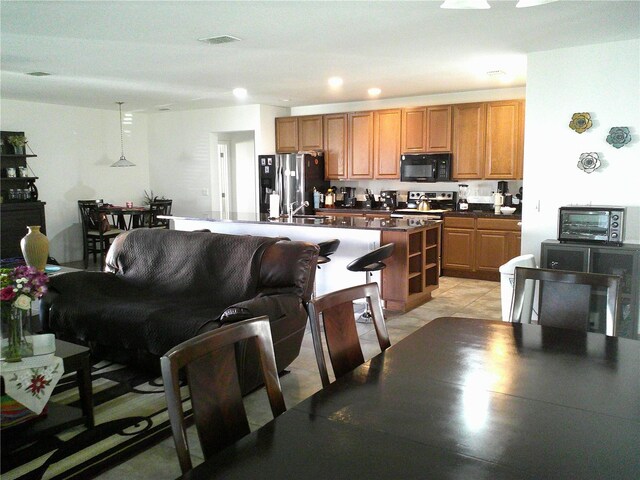 kitchen featuring stainless steel appliances, sink, light tile patterned floors, a center island, and hanging light fixtures