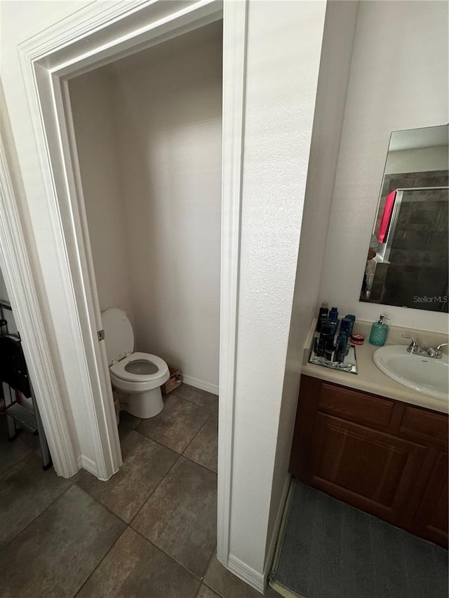 bathroom featuring tile patterned flooring, vanity, toilet, and a shower with shower door