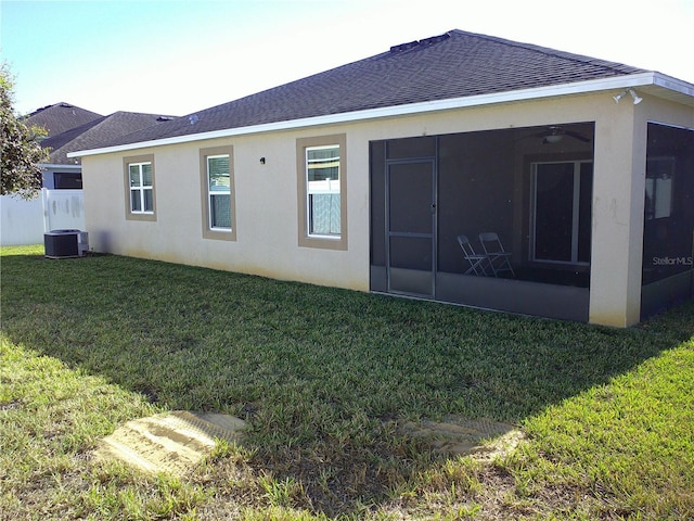 rear view of property with a sunroom, cooling unit, and a lawn