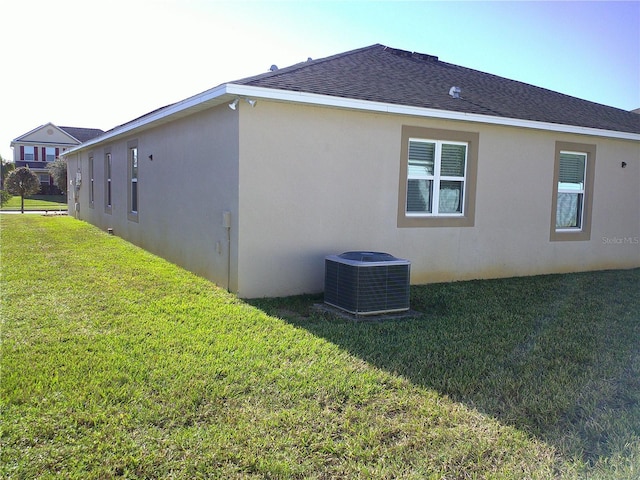 view of side of property with a yard and central air condition unit