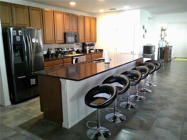 kitchen featuring a kitchen bar, appliances with stainless steel finishes, a center island with sink, and sink