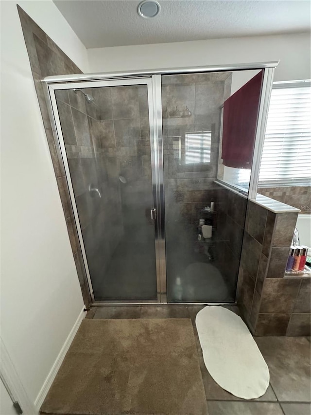 bathroom featuring a shower with shower door and a textured ceiling