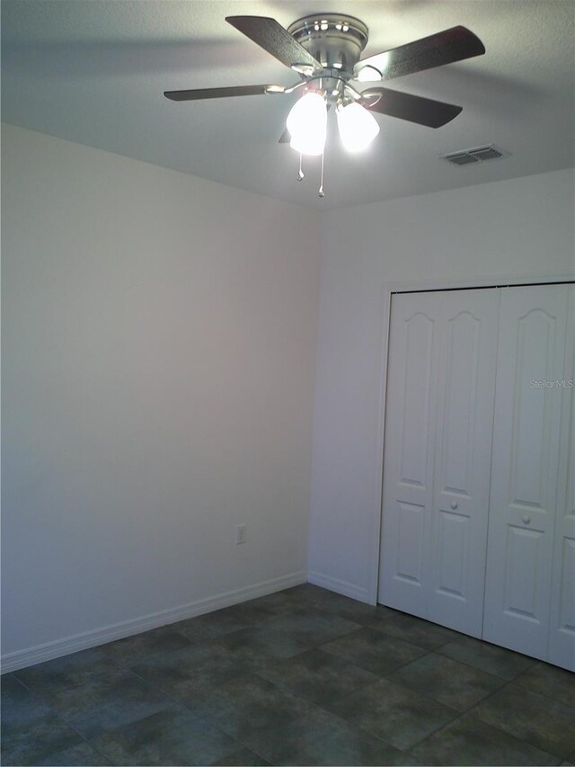 unfurnished bedroom with ceiling fan and a closet