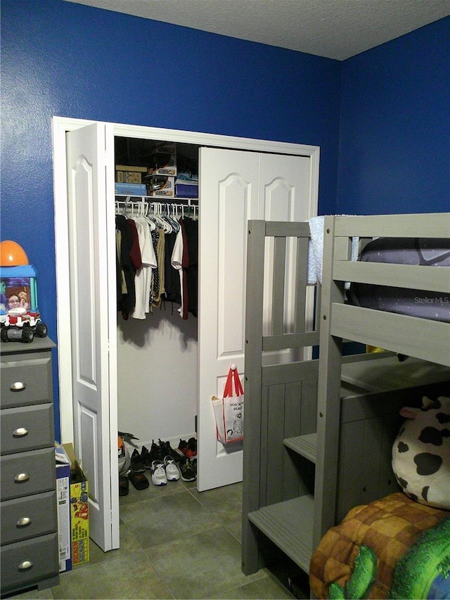 bedroom featuring a closet, a textured ceiling, and tile patterned flooring