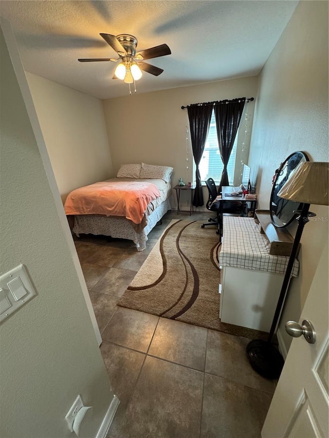 bedroom featuring ceiling fan, dark tile patterned flooring, and a textured ceiling