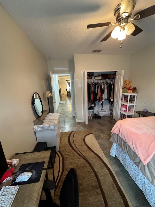 tiled bedroom with ceiling fan, a textured ceiling, and a closet