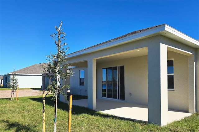 rear view of property featuring a lawn and a patio area