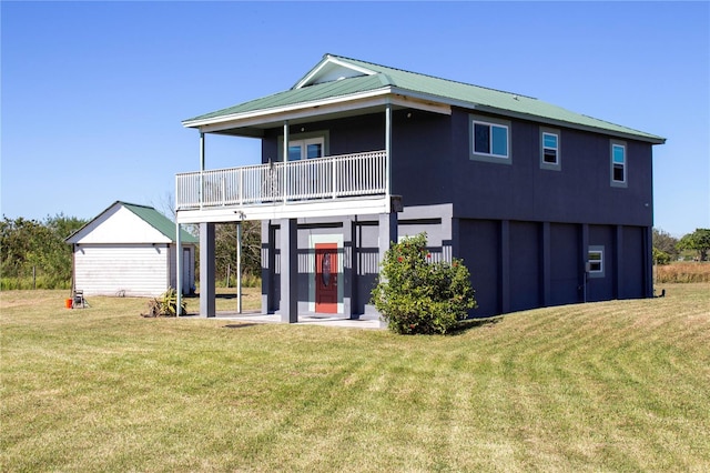 back of house with a lawn, a garage, a balcony, and an outdoor structure