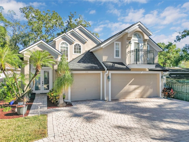 view of front of home featuring french doors, a balcony, and a garage