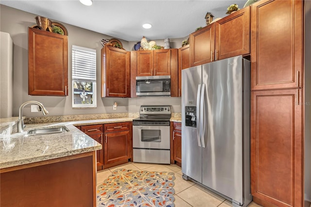 kitchen with light stone counters, sink, light tile patterned floors, and stainless steel appliances