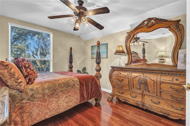 bedroom with a textured ceiling, hardwood / wood-style flooring, vaulted ceiling, and ceiling fan